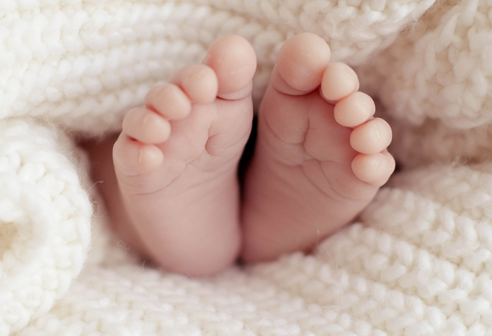Close up of baby feet in a white knitted blanket.
