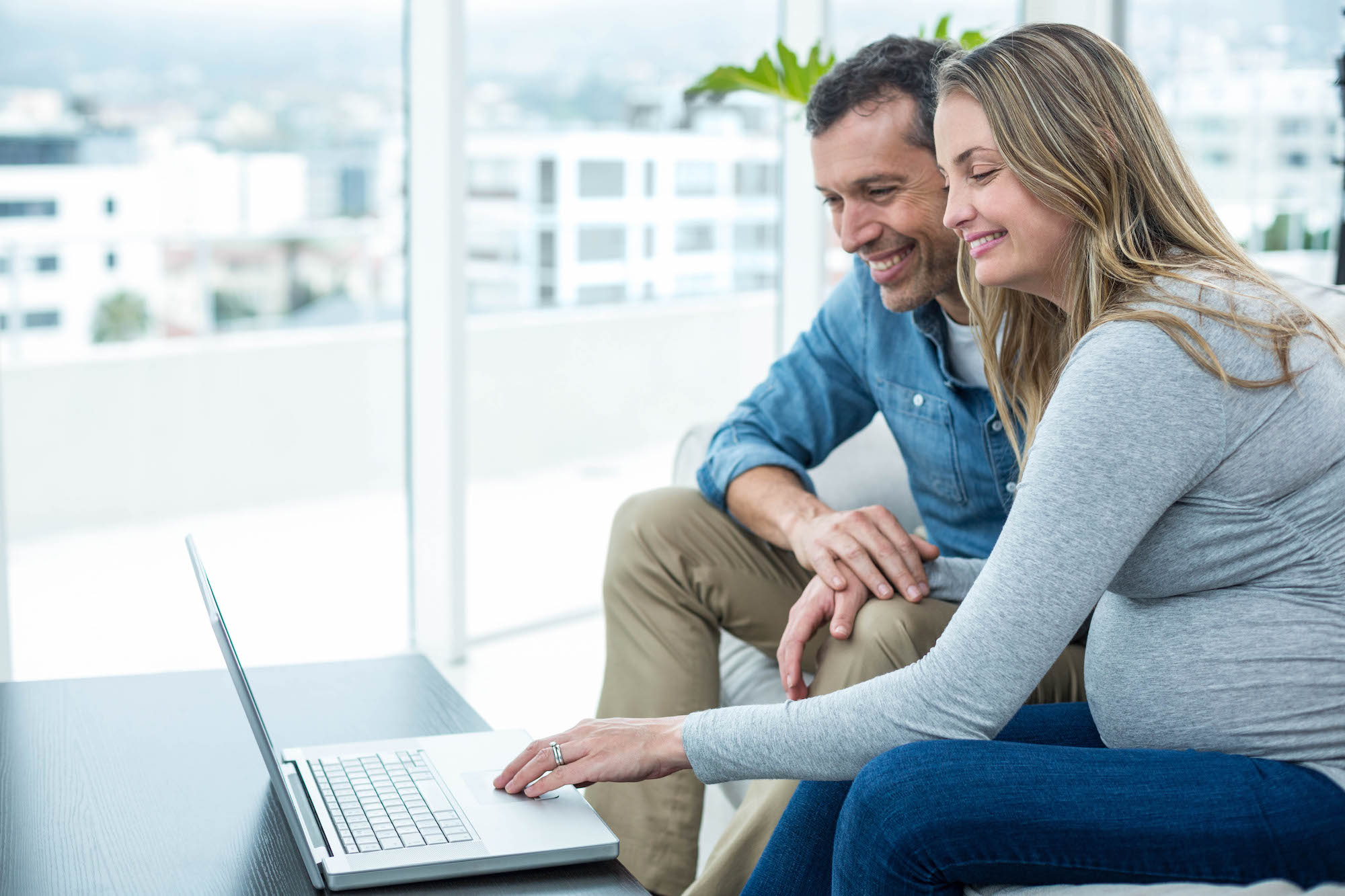 Heterosexual white couple looking at laptop and smiling.
